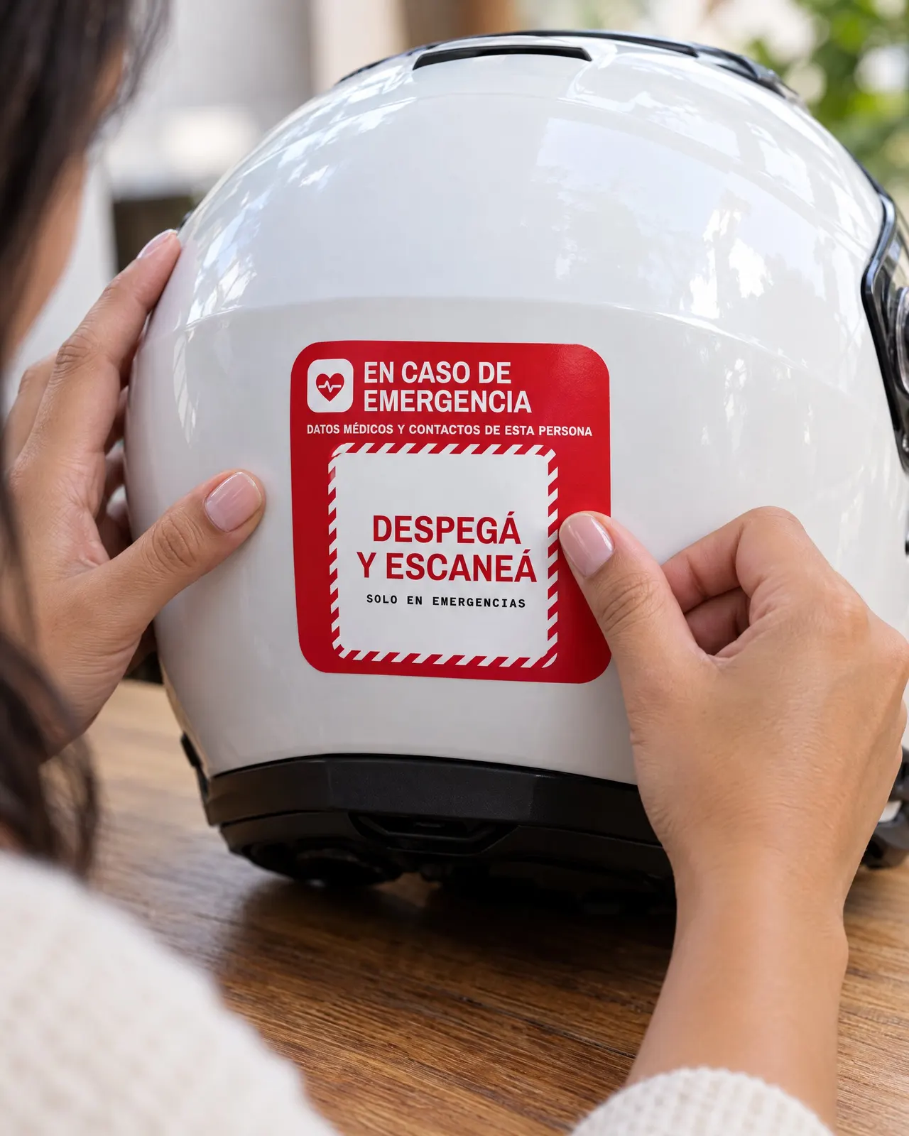 Manos pegando el sticker rojo de Mi Vida ID en un casco blanco